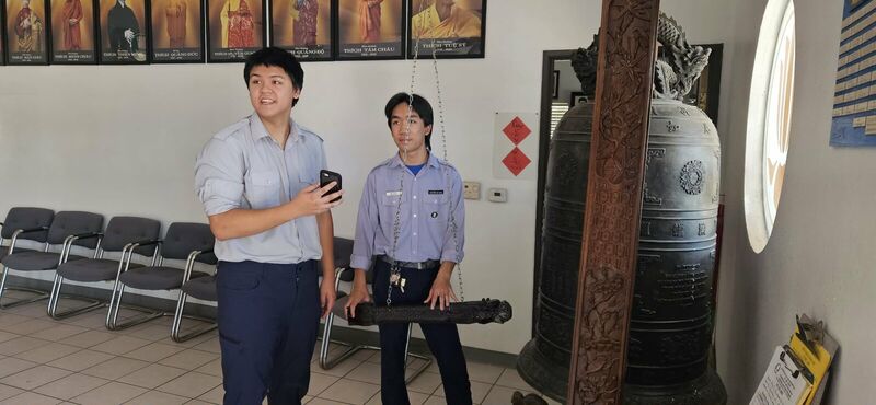 Huynh Trưởng tập sự đứng cạnh đại hồng chung chuẩn bị thỉnh chuông