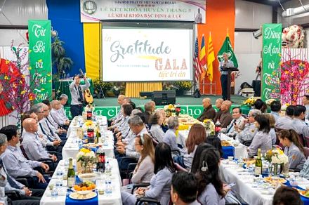 Bàn tiệc dài trước màn hình chiếu chữ Gratitude Gala