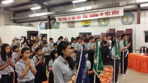 Đoàn sinh cầm cờ đứng nghiêm trong hội trường, cờ Phật giáo và cờ Hoa Kỳ hai bên