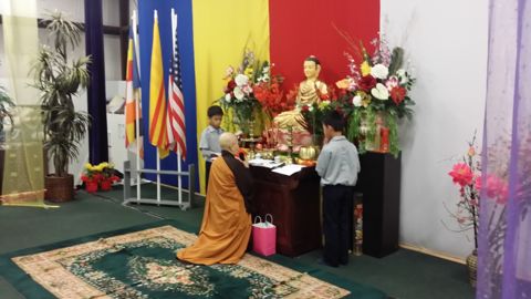 Sư Cô Tịnh Ngọc đứng trước bàn Phật, một em đoàn sinh đứng nghiêm bên cạnh