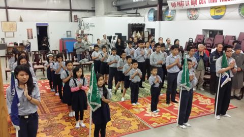 Các em đứng thành hàng chắp tay chào cờ, Huynh Trưởng đứng phía trước