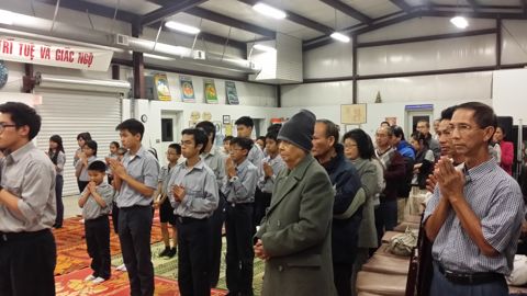 Hàng đầu đoàn sinh chắp tay, phía sau là các bậc phụ huynh đứng chắp tay theo
