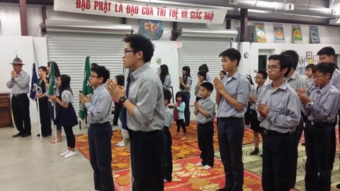 Các em Ngành Thiếu chắp tay tụng kinh, bên trên là biểu ngữ Đạo Phật là đạo của trí tuệ và giác ngộ