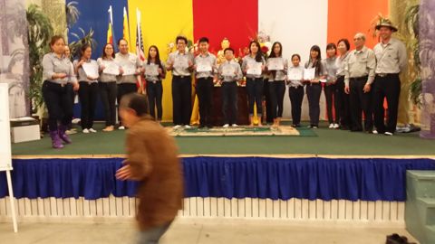 Hàng đoàn sinh Ngành Thiếu cầm chứng chỉ trên sân khấu, cờ ba màu phía sau