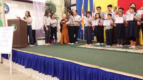 Huynh Trưởng trao chứng chỉ cho các em, phụ huynh chụp hình từ dưới sân khấu