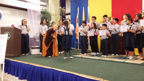 Các em Oanh Vũ nhỏ cầm chứng chỉ đứng trên sân khấu, Huynh Trưởng đội nón đứng bên