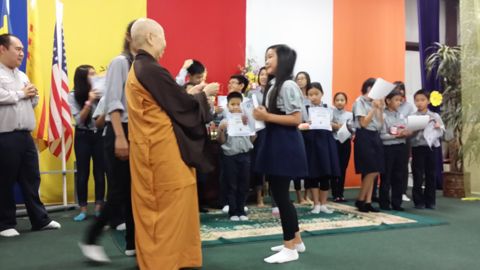 Sư Cô Tịnh Ngọc đi dọc hàng các em Oanh Vũ đang cầm chứng chỉ trên sân khấu