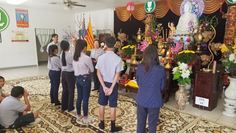 Cả gia đình đứng trước bàn thờ Phật và bốn lá cờ
