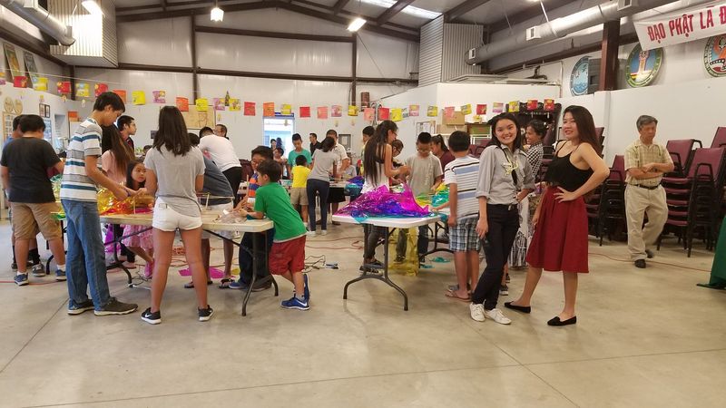Phụ huynh và đoàn sinh đứng quanh các bàn làm lồng đèn trong hội trường