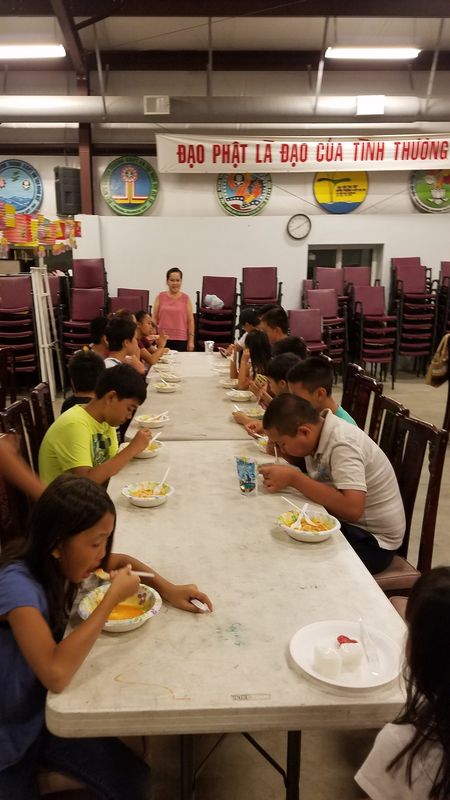Các em ngồi quanh bàn dài ăn uống cuối đêm Trung Thu tại Trung Tâm Thích Quảng Đức